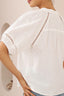 White blouse with intricate detailing on the sleeves and neckline against a neutral background