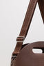 Close-up of a brown leather bag with a strap on a light gray background