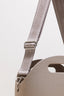 Close-up of a beige bag with a strap and visible brand name on a light gray background