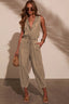 Woman wearing a beige jumpsuit against a plain background